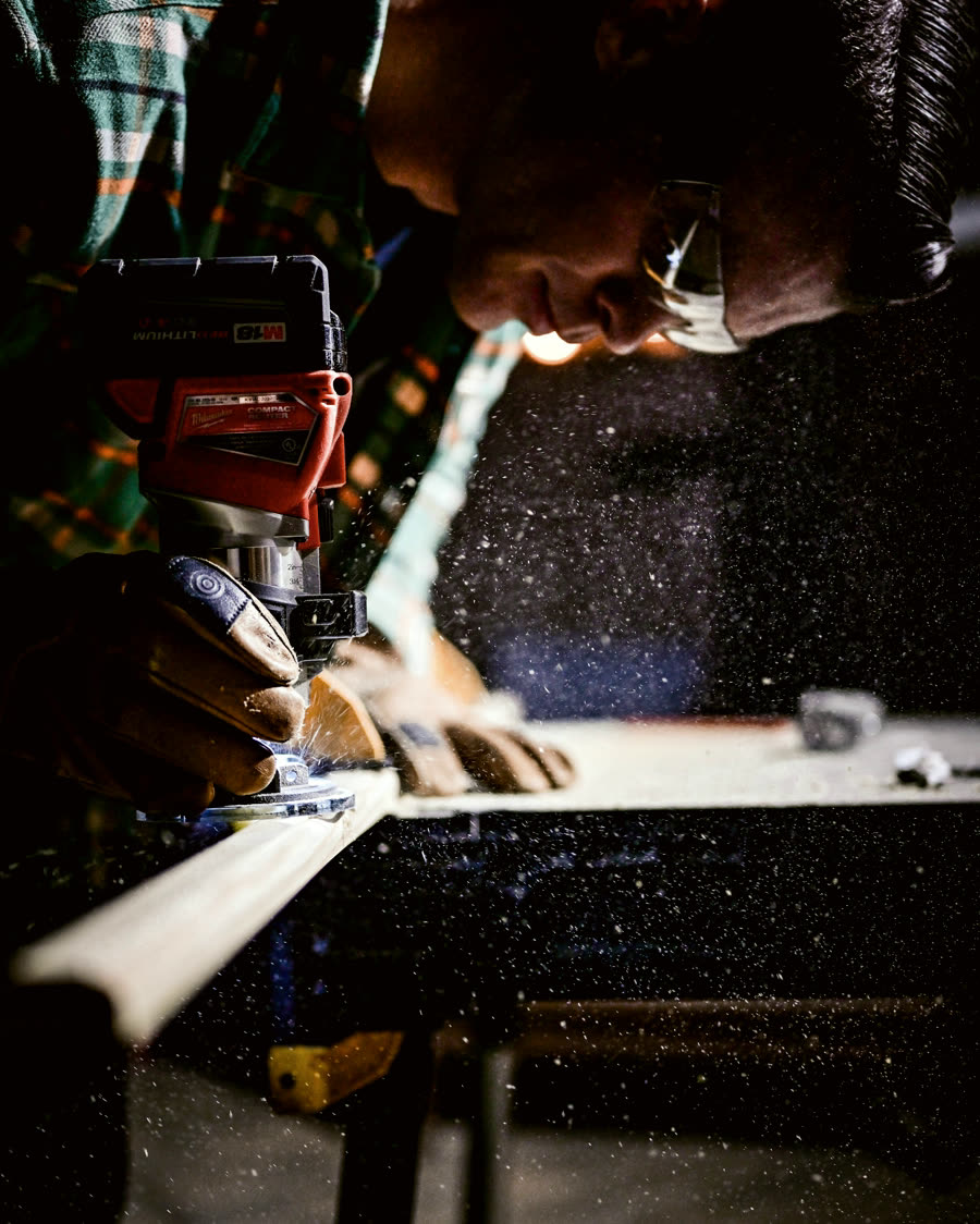 A tradesperson cutting timber on site, gloved hands on the saw
