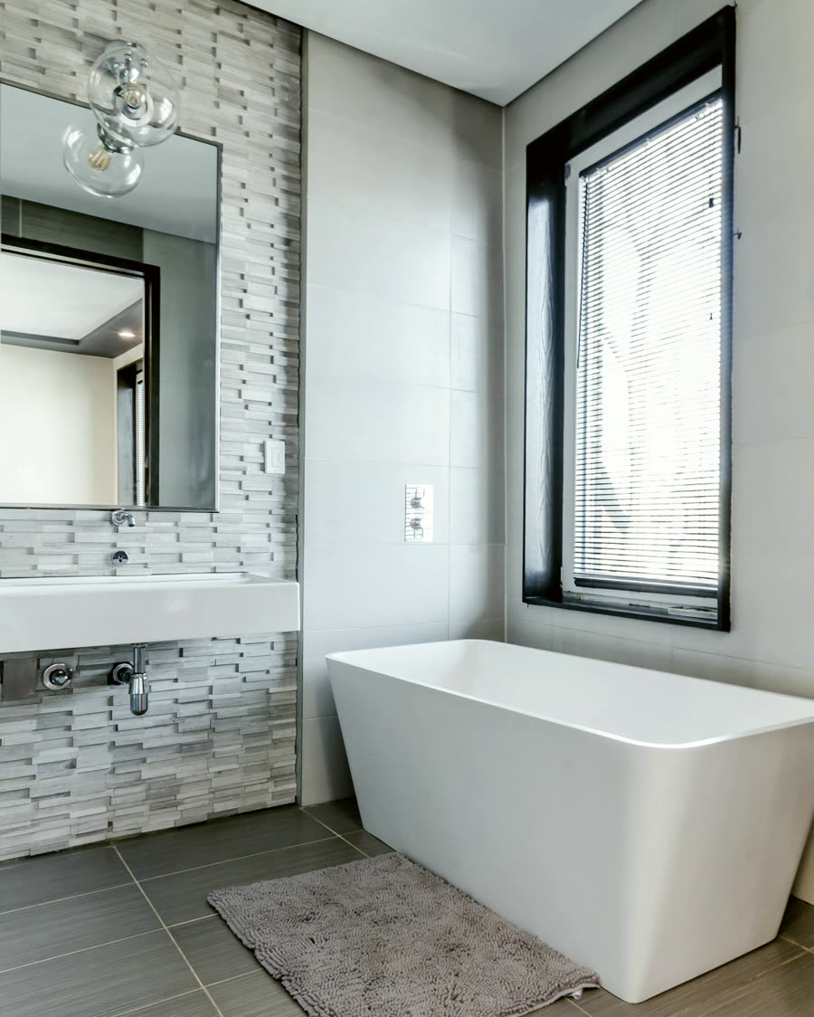 A main bathroom with a freestanding tub beside a tall window