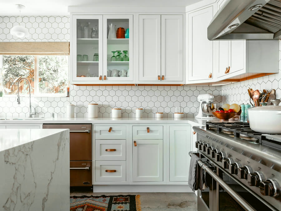 A kitchen in white shaker and marble with unlacquered brass fittings