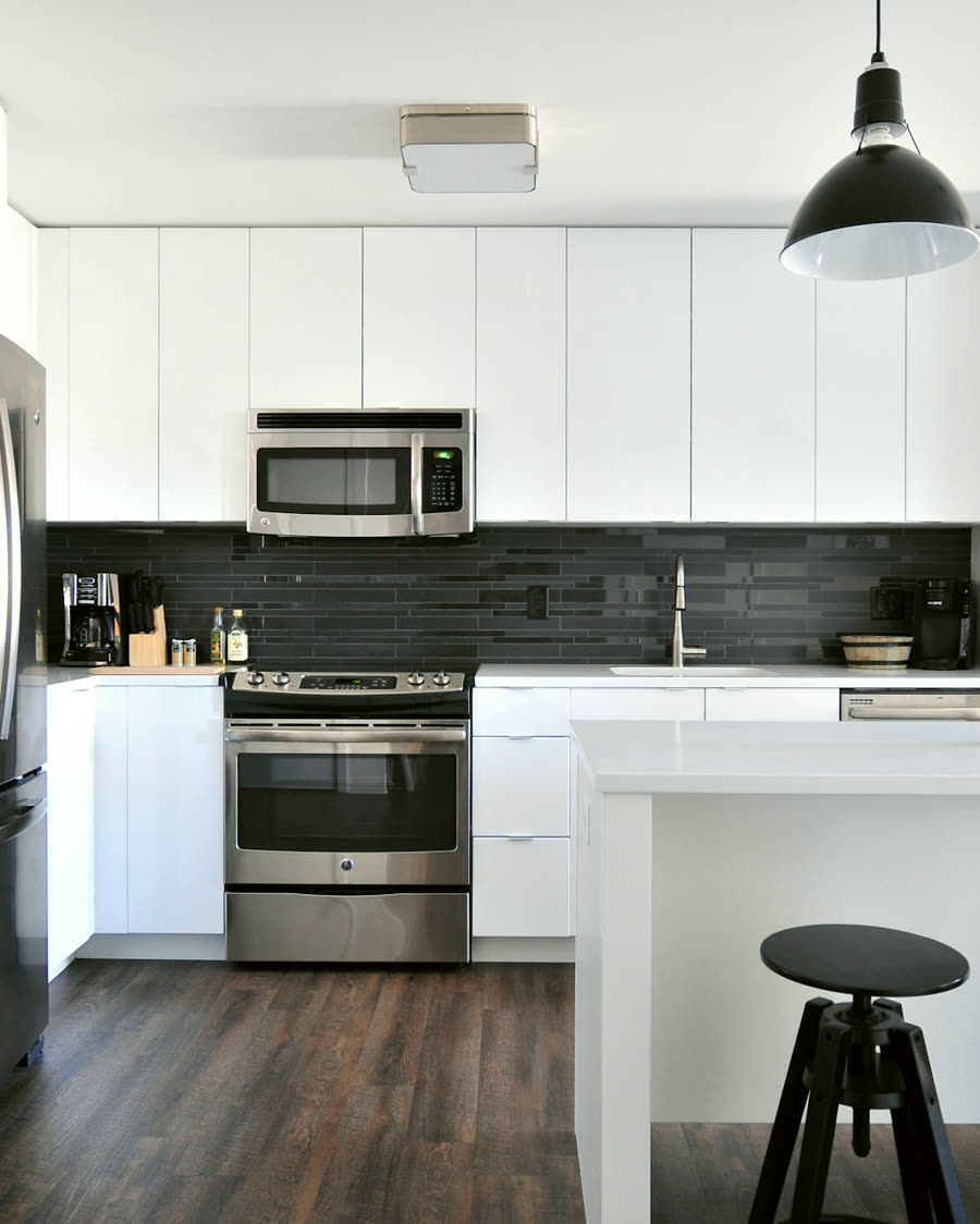 A finished kitchen in painted shaker with a dark stone backsplash