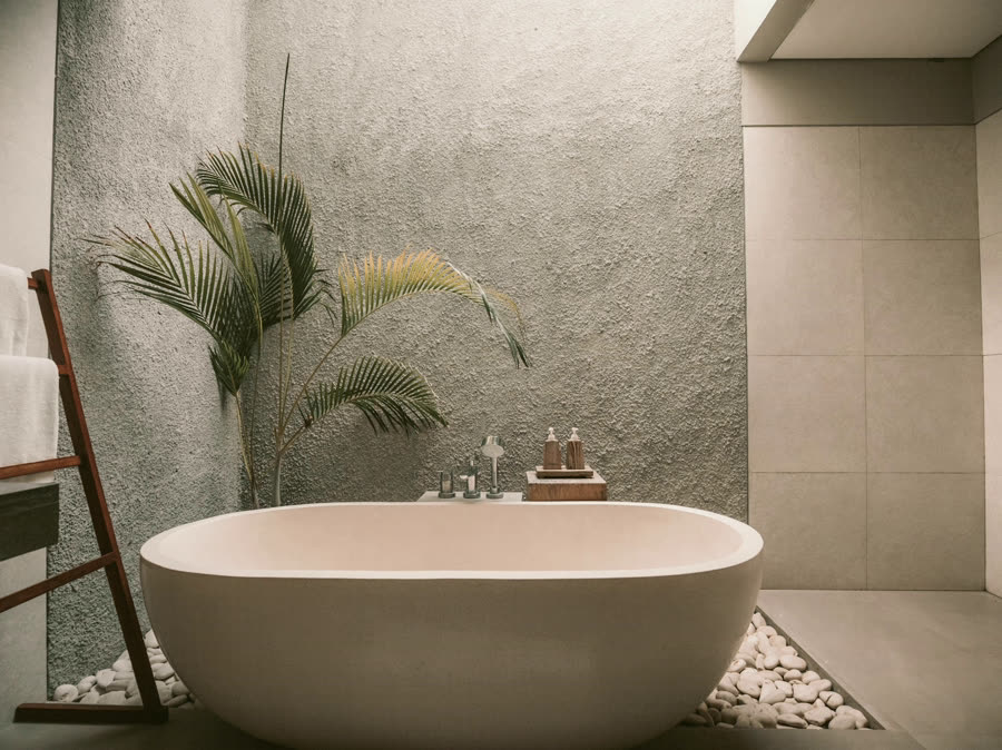 An ensuite with a stone bath against a lime plaster wall